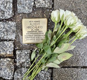 Stolperstein von Albert Hirschland mit weißen Rosen