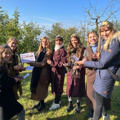 Die Weinköniginnen stehen im Halbkreis und präsentieren die Flyer mit Bildungsurlauben
