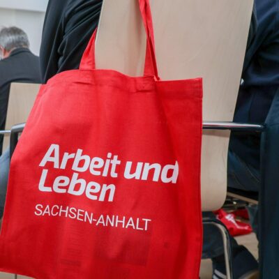 Blick in eine Veranstaltung von Arbeit und Leben Sachsen-Anhalt mit Fokus auf einen Beutel mit Logo.
