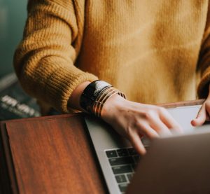 eine tippende Person sitzt am Laptop