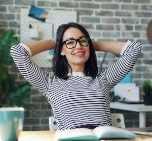 Eine Person sitzt mit verschränkten Händen und in entspannter Pose am Schreibtisch.