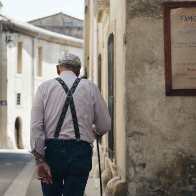 ein Rentner geht eine Straße entlang