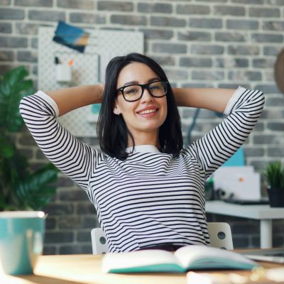 Eine Person sitzt mit verschränkten Händen und in entspannter Pose am Schreibtisch.