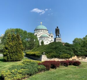 Zu sehen ist die markante Kirche des Heiligen Sava (eine der größten orthodoxen Kirchen der Welt) mit ihrer großen grünlichen Kuppel und davor die Statue von Karađorđe (Đorđe Petrović), in Belgrad.