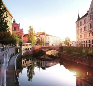 Sicht auf Ljubljana mit einem mäandernden Fluss in der Mitte, über den eine Brücke führt