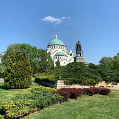 Zu sehen ist die markante Kirche des Heiligen Sava (eine der größten orthodoxen Kirchen der Welt) mit ihrer großen grünlichen Kuppel und davor die Statue von Karađorđe (Đorđe Petrović), in Belgrad.