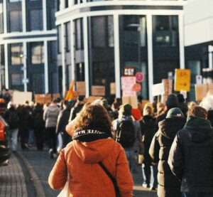 blick in eine Straßenschlucht. Es sind demonstrierende Menschen unterwegs.