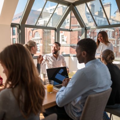 Eine Gruppe von Menschen sitzt an einem Tisch mit Laptops und diskutiert.
