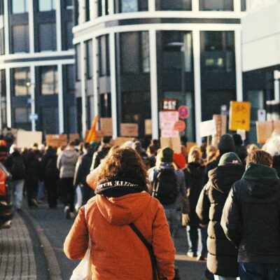 blick in eine Straßenschlucht. Es sind demonstrierende Menschen unterwegs.