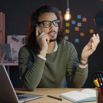 Mann mit Brille telefoniert im Dunkeln am Laptop