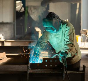 ein Schweißer, der an einem Stück Metall arbeitet