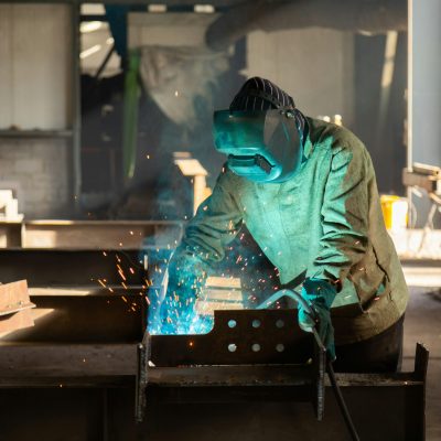 ein Schweißer, der an einem Stück Metall arbeitet