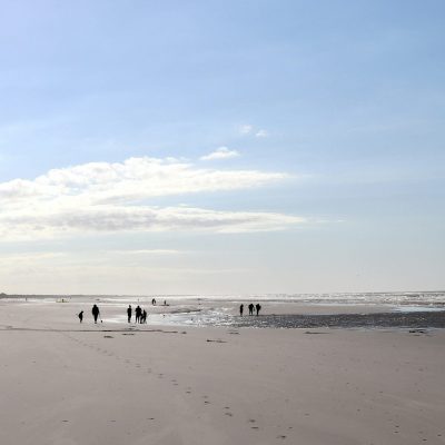 Blick auf einen Strand bei Ebbe mit mehreren Menschen