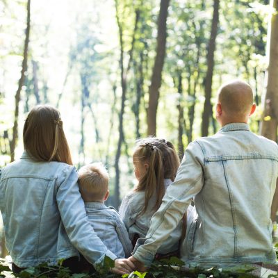 eine Familie sitzt zusammen im grünen Wald