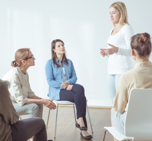 Eine blonde Frau spricht vor vier Frauen, die im Halbkreis vor ihr sitzen.