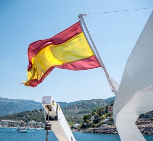 Eine spanische Flagge weht am heck eines Bootes vor blauem Himmel
