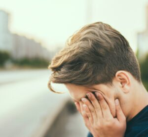 eine erschöpfte Person hält die Hände vor das Gesicht