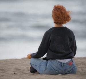 Achtsame Person sitzt am Strand.