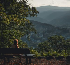 eine Person sitzt auf einer Bank im Harz und blickt zum Brocken