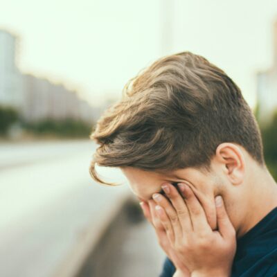 an exhausted person holds their hands in front of their face