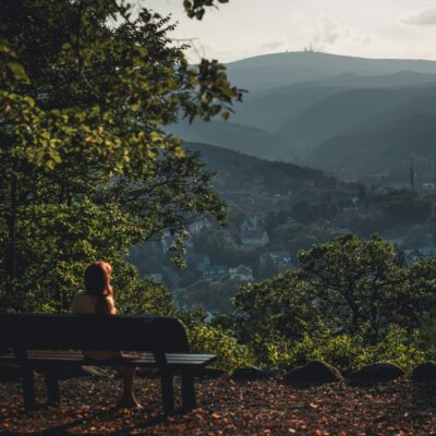 eine Person sitzt auf einer Bank im Harz und blickt zum Brocken