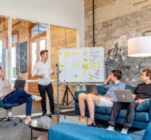 Ein Team von vier Männern bespricht an einem Whiteboard geplante Veränderungen und neue Arbeitsabläufe im Unternehmen.