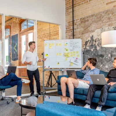 Ein Team von vier Männern bespricht an einem Whiteboard geplante Veränderungen und neue Arbeitsabläufe im Unternehmen.