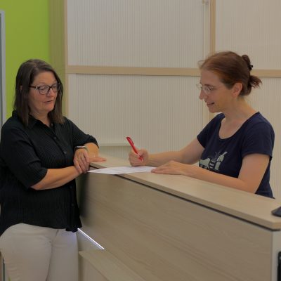 Eine Frau berät eine Person zu den Angeboten von Arbeit Und Leben Niedersachsen im Eingangsbereich der Geschäftsstelle Braunschweig.