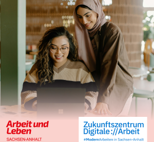 Eine Frau sitzt am Tisch am Laptop. Eine zweite mit Kopftuch steht hinter ihr und lehnt sich nach vorn, um auf den Bildschirm gucken zu können.