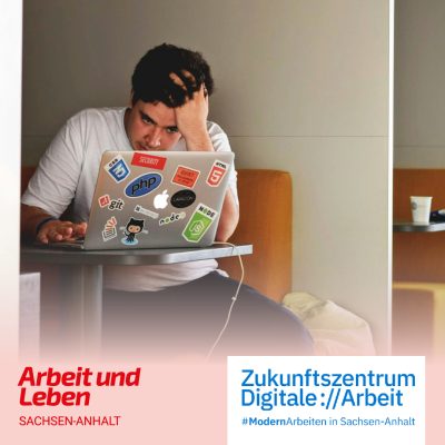 Ein Mann sitzt in einer Arbeitsniesche am Laptop. Er hat den Kopf abgestützt und wirkt getresst.