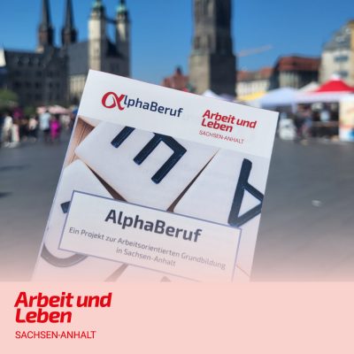 Der Flyer vom Projekt AlphaBeruf wird vor die Kamera gehalten, im Hintergrund der Marktplatz von Halle (Saale).